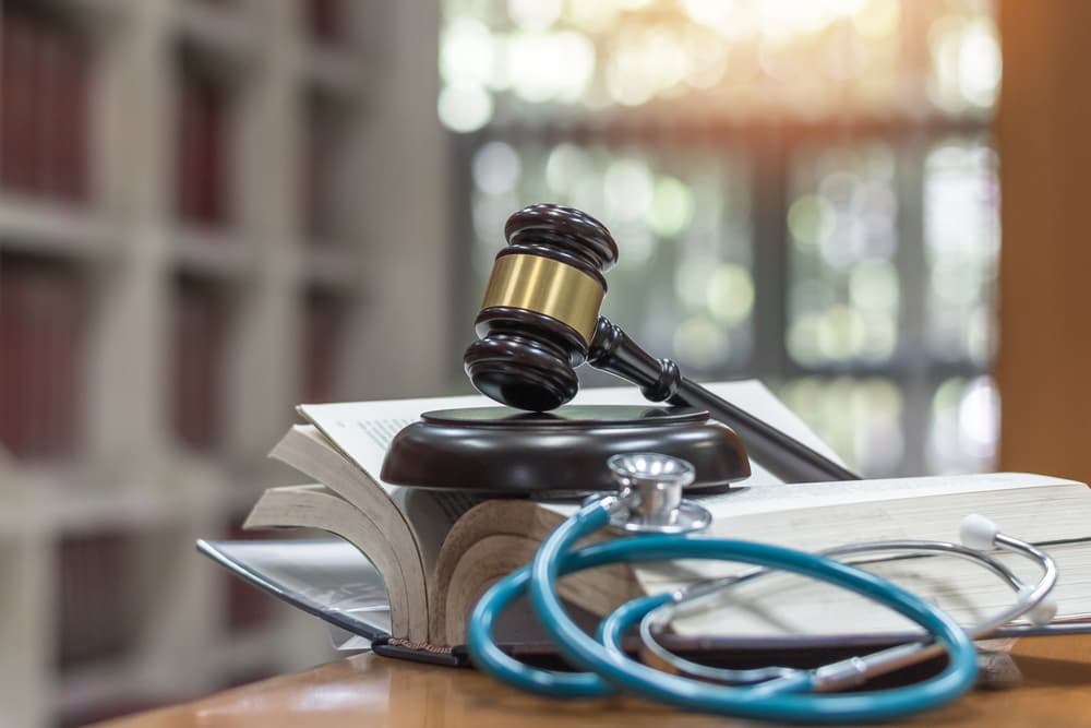 Forensic medicine and criminalistics concept with a judge's gavel resting on a law textbook, symbolizing legal investigations and justice in medical practice.