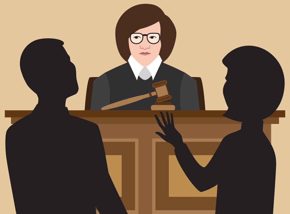 Female judge listening attentively as two lawyers argue their cases in a courtroom.