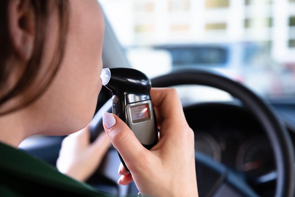 Close-up of a woman's mouth as she undergoes an alcohol breath test, highlighting the seriousness of DUI testing and its implications.