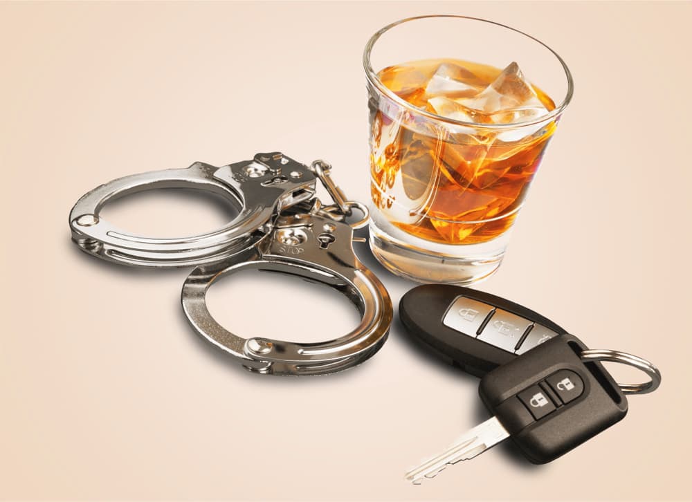 Whiskey alongside car keys and handcuffs, representing the consequences of drunk driving and the legal implications that follow.