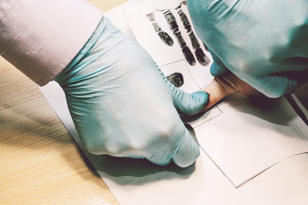 Investigator fingerprinting a crime suspect during a criminal investigation process.