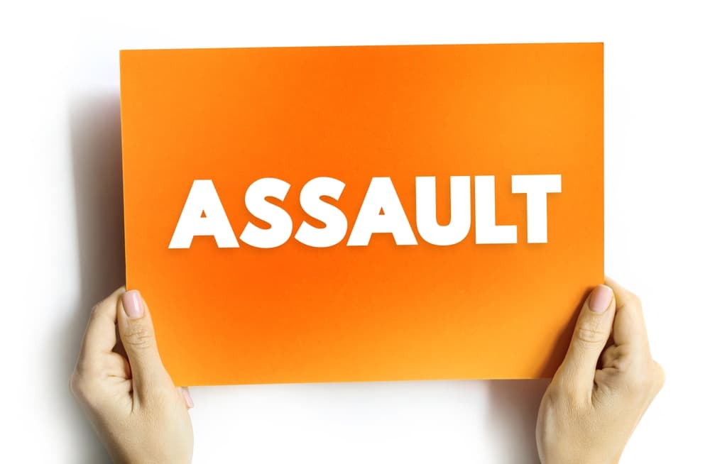 Assault: The act of causing physical harm or unwanted physical contact to another person. Text concept on a card.