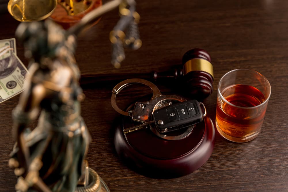 Whiskey accompanied by car keys and handcuffs—a symbolic concept illustrating the dangers and legal consequences of drinking and driving.






