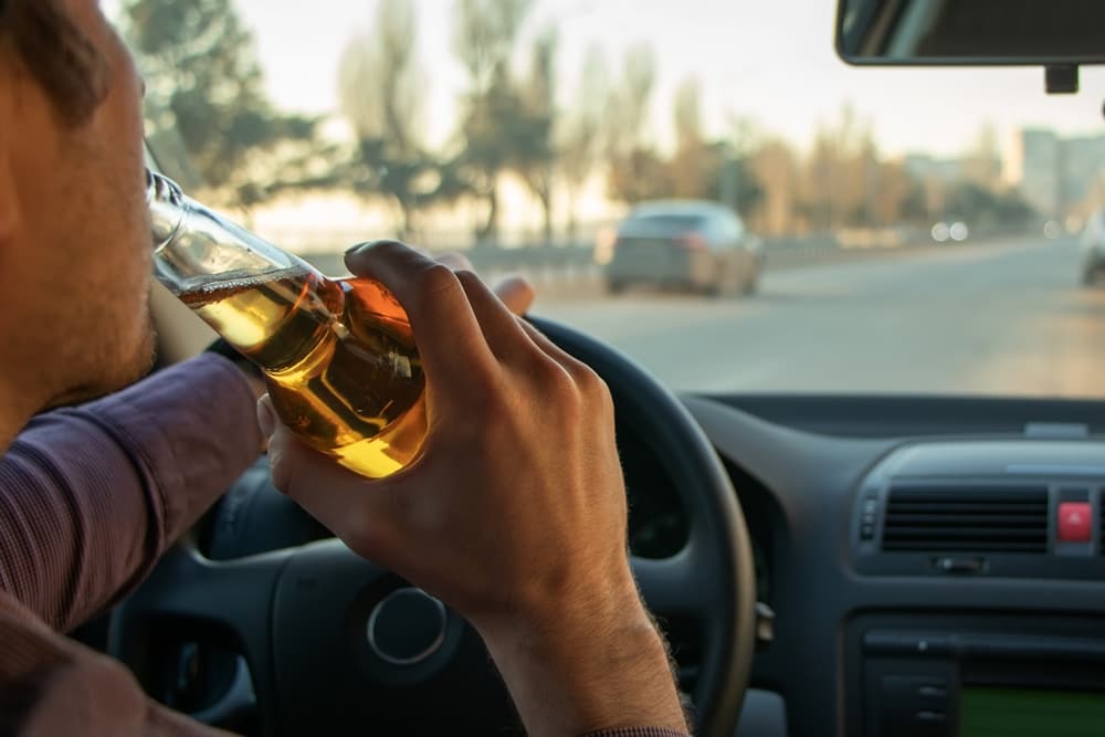 A man drinking alcohol while driving. Drunk driving concept.