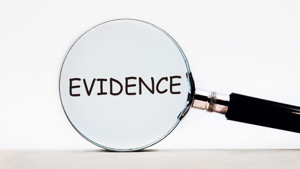 Looking through a magnifying glass at the word Evidence,.