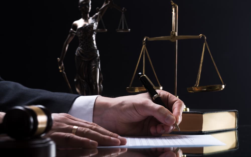 A wooden judge's gavel and a businessman in a courtroom setting.