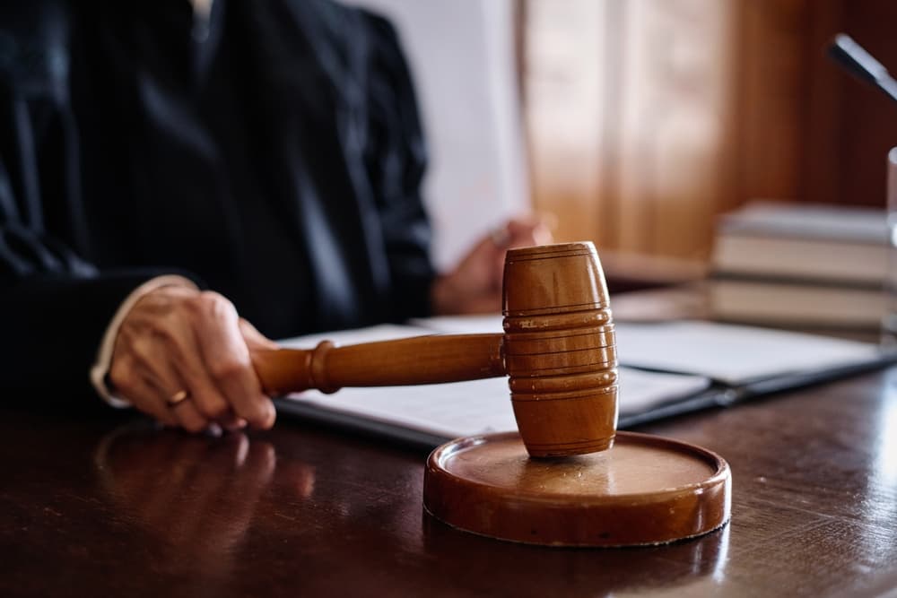 A Supreme Court judge striking a sounding block with a wooden gavel in a courtroom.