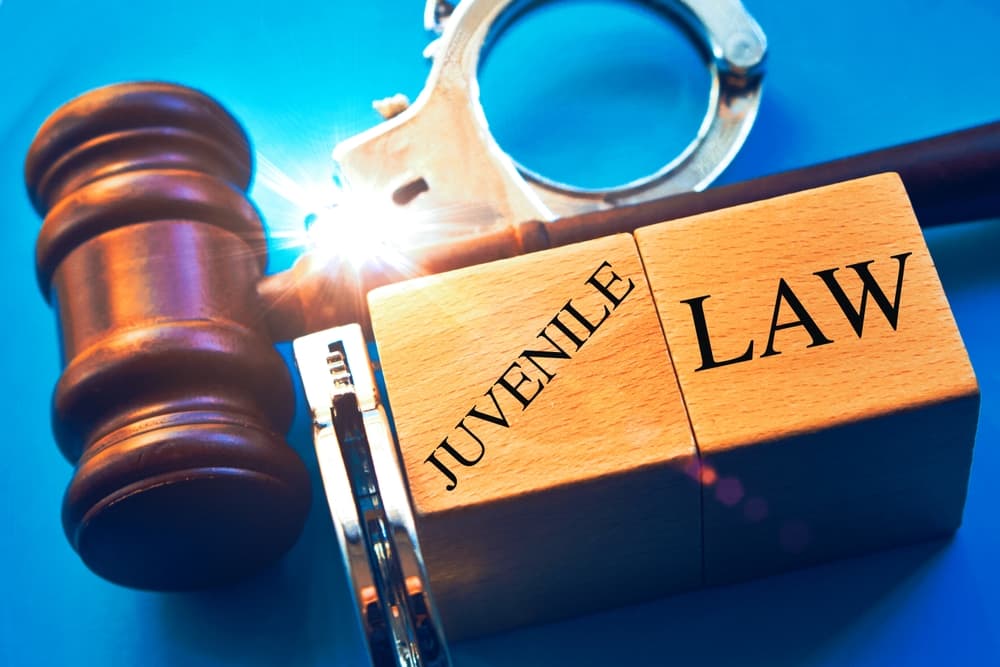 "Juvenile law" with a gavel and handcuffs against a blue background.






