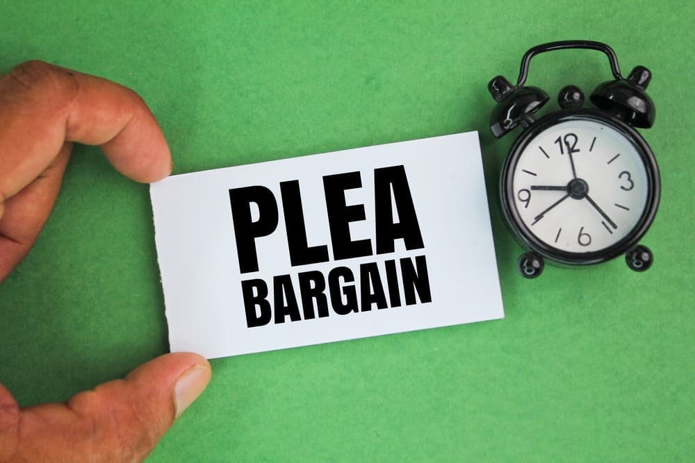 An alarm clock beside a hand holding a white paper labeled "Plea Bargain," symbolizing the urgency and timing involved in court appeals and legal decisions.