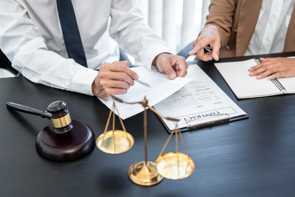 A businesswoman and a male lawyer consult with a client during a team meeting at a law firm, discussing legal services and professional guidance.