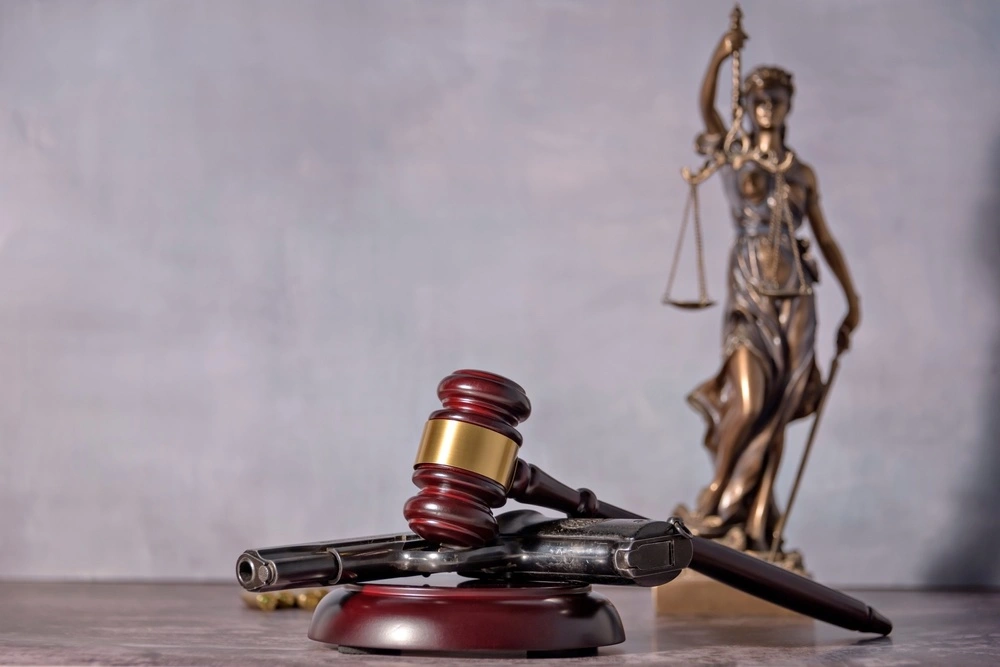 Gun, gavel, and Lady Justice statue, illustrating how California's 10-20-Life firearm enhancement law can add significant prison time to a criminal sentence.