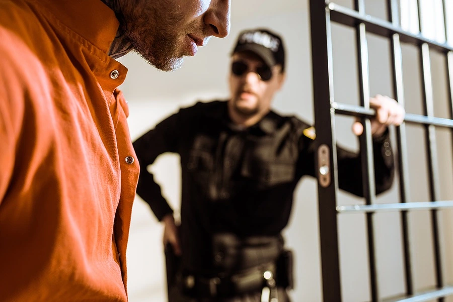 Person being escorted to a jail cell, illustrating the charges and legal defenses involved in a California Penal Code § 243.4 sexual battery case.